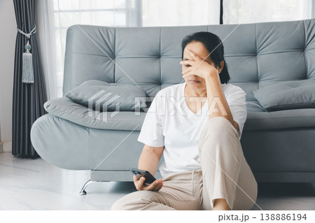 Depressed woman sitting on floor by gray sofa, hand on face, holding smartphone at home. Mental health anxiety, burnout and loneliness concept for therapy, support, awareness, copy space. depressed Depressed woman sitting on floor by gray sofa, hand on face, holding smartphone at home. Mental health anxiety, burnout and loneliness concept for therapy, support, awareness, copy space. depressed 138886194