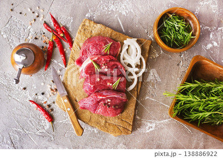 Juicy raw piece of selected veal with spices and herbs, on a stone background. Veal, steak. Top view. 138886922