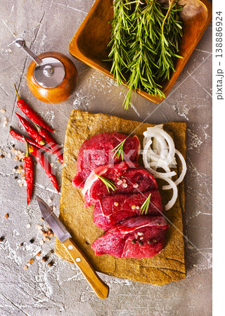 Juicy raw piece of selected veal with spices and herbs, on a stone background. Veal, steak. Top view. 138886924