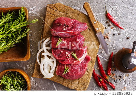 Juicy raw piece of selected veal with spices and herbs, on a stone background. Veal, steak. Top view. 138886925