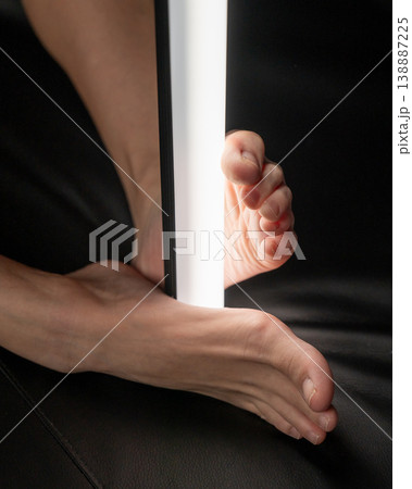 A woman holds an LED lamp with her feet. Foot fetish.  138887225
