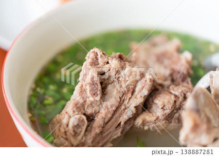 Hot and spicy pork bone soup with herbs and clear broth Thai tom saep featuring tender meat and rich flavor traditional comfort food with fresh green garnish closeup detail 138887281