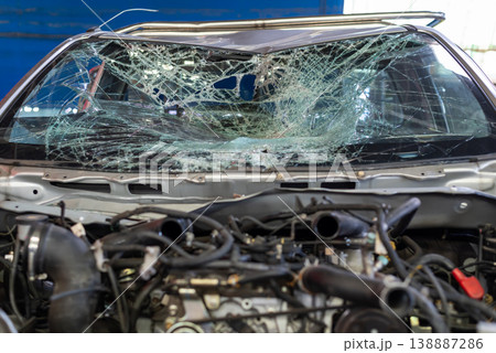 Broken car windshield with severe cracks and impact damage inside vehicle showing accident aftermath and safety risk with visible engine bay and workshop environment Broken car windshield with severe cracks and impact damage inside vehicle showing accident aftermath and safety risk with visible engine bay and workshop environment 138887286