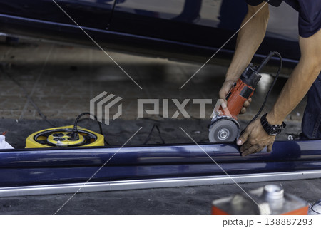 Technician polishing car body with electric angle grinder showing surface refinement and detailing process in garage environment highlighting automotive maintenance and repair work Technician polishing car body with electric angle grinder showing surface refinement and detailing process in garage environment highlighting automotive maintenance and repair work 138887293