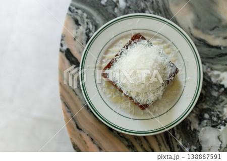 Fresh bread butter toast with Vanilla flavor ice cream topped with grated Parmesan cheese on white ceramic plate on marble table. Fresh bread butter toast with Vanilla flavor ice cream topped with grated Parmesan cheese on white ceramic plate on marble table. 138887591