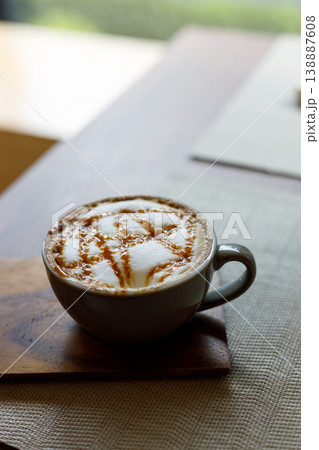Cup of hot milk caramel macchiato coffee on table by the window. Cup of hot milk caramel macchiato coffee on table by the window. 138887608