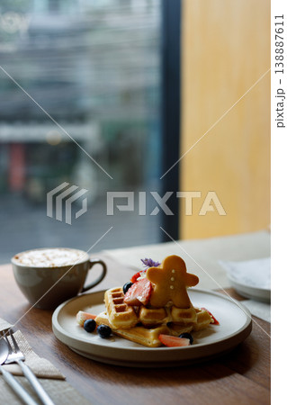Cup of hot milk caramel macchiato coffee and plate of waffles on table by the window. Cup of hot milk caramel macchiato coffee and plate of waffles on table by the window. 138887611