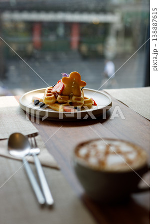 Cup of hot milk caramel macchiato coffee and plate of waffles on table by the window. Cup of hot milk caramel macchiato coffee and plate of waffles on table by the window. 138887615