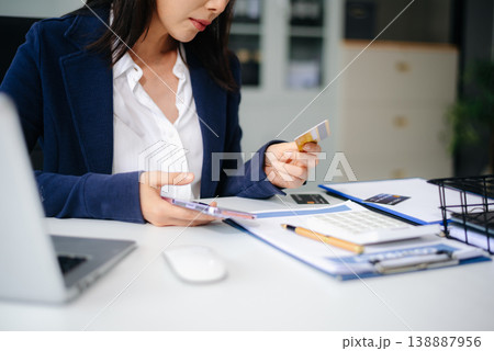 Stressed Asian businesswoman holding multiple credit cards in office, facing financial pressure. Stressed Asian businesswoman holding multiple credit cards in office, facing financial pressure. 138887956