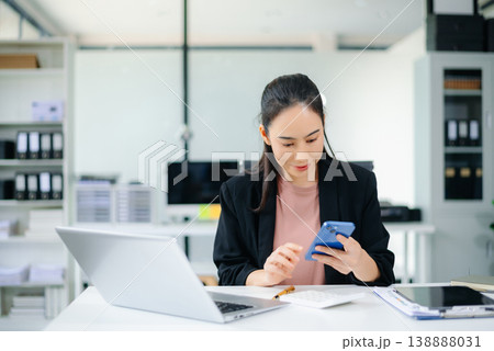 Confident Asian businesswoman using tablet in modern office with laptop and documents, showcasing finance, remote work Confident Asian businesswoman using tablet in modern office with laptop and documents, showcasing finance, remote work 138888031