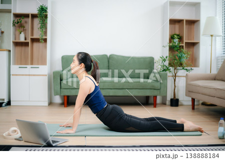 Young Asian woman practicing yoga indoors on a mat. Calm, healthy lifestyle, stretching, wellness and fitness at home Young Asian woman practicing yoga indoors on a mat. Calm, healthy lifestyle, stretching, wellness and fitness at home 138888184