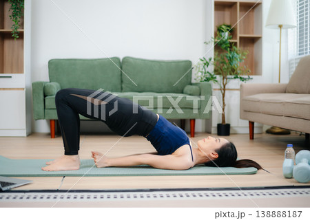 Asian woman doing yoga on a mat at home. Indoor fitness, healthy lifestyle, calm energy, stretching pose in a peaceful living room Asian woman doing yoga on a mat at home. Indoor fitness, healthy lifestyle, calm energy, stretching pose in a peaceful living room 138888187