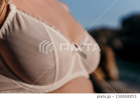 Lingerie white mesh woman wearing delicate white lace bra on a sunny rocky coast during golden hour for summer fashion Lingerie white mesh woman wearing delicate white lace bra on a sunny rocky coast during golden hour for summer fashion 138888853