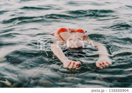 Woman ocean floating, serene lady in red swimsuit enjoying summer water relaxation Woman ocean floating, serene lady in red swimsuit enjoying summer water relaxation 138888904