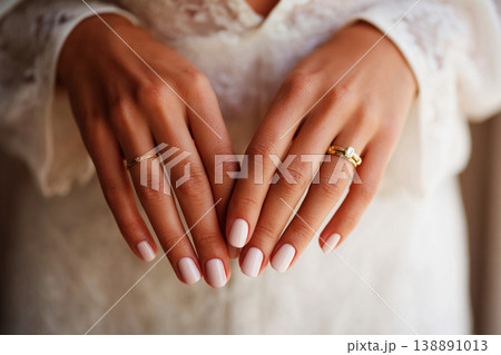 Bridal hands rest gently on soft fabric, showcasing a modern manicure. The setting suggests a wedding preparation moment full of anticipation and joy Bridal hands rest gently on soft fabric, showcasing a modern manicure. The setting suggests a wedding preparation moment full of anticipation and joy 138891013