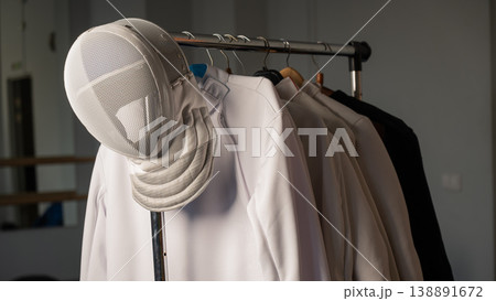 Fencing uniforms and masks hang on hangers. No people.  138891672