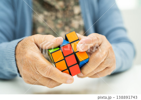 Bangkok, Thailand August 14, 2023 Alzheimer disease AD, Asian elderly woman patient playing Rubik cube game to practice brain training for dementia prevention. 138891743