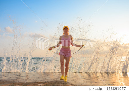 Fit woman jumping rope at the beach during summer vacation Fit woman jumping rope at the beach during summer vacation 138891977