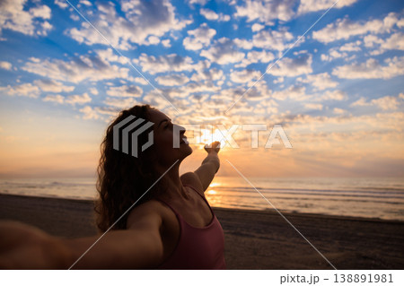 Happy woman enjoying sunrise at the beach during summer vacation Happy woman enjoying sunrise at the beach during summer vacation 138891981