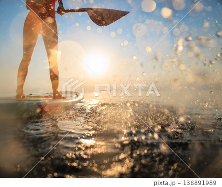 Women's legs on sup board by the sea during summer vacation Women's legs on sup board by the sea during summer vacation 138891989