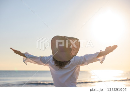 Young happy woman enjoys the summer sun on the beach during the sunrise Young happy woman enjoys the summer sun on the beach during the sunrise 138891995