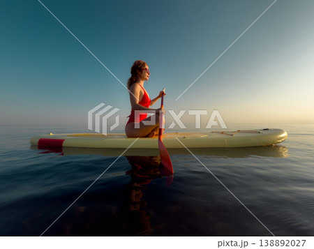 Young woman walking on sup board by the sea during summer vacation Young woman walking on sup board by the sea during summer vacation 138892027