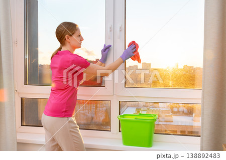 A woman is washing a window in a room 138892483