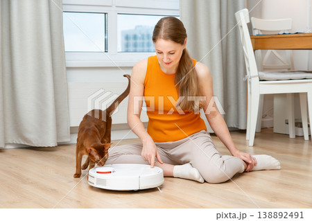 Woman turns on a robot vacuum cleaner Woman turns on a robot vacuum cleaner 138892491