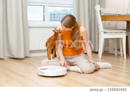 Woman turns on a robot vacuum cleaner 138892492