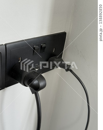 Electrical outlet with two black plugs on a white wall providing power connection background Electrical outlet with two black plugs on a white wall providing power connection background 138892850