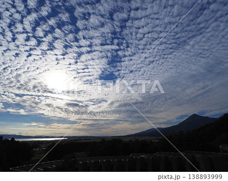 猪苗代湖上空に輝く夕日。シルエットの磐梯山に湖面の輝きが鱗雲の秋空に印象的で綺麗だ。 猪苗代湖上空に輝く夕日。シルエットの磐梯山に湖面の輝きが鱗雲の秋空に印象的で綺麗だ。 138893999