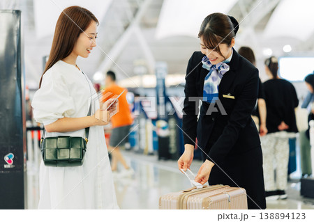 旅行者のキャリーバッグにタグをつける空港の女性グランドスタッフ　「撮影協力：関西国際空港（KIX）」 138894123