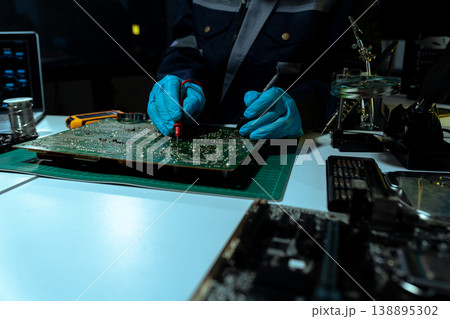 Computer Hardware Technician Repairing Motherboard with Soldering Iron in Electronics Lab. 138895302