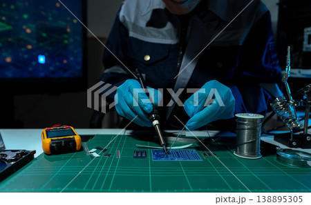 Computer Hardware Technician Repairing Motherboard with Soldering Iron in Electronics Lab. 138895305