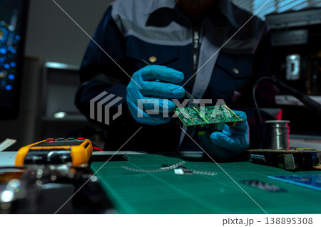 Computer Hardware Technician Repairing Motherboard with Soldering Iron in Electronics Lab. 138895308