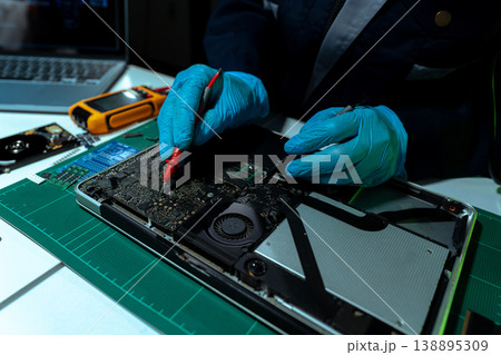 Computer Hardware Technician Repairing Motherboard with Soldering Iron in Electronics Lab. 138895309