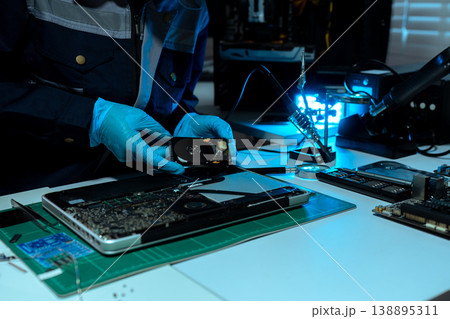 Computer Hardware Technician Repairing Motherboard with Soldering Iron in Electronics Lab. 138895311