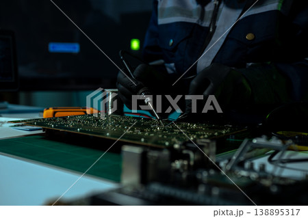 Computer Hardware Technician Repairing Motherboard with Soldering Iron in Electronics Lab. 138895317
