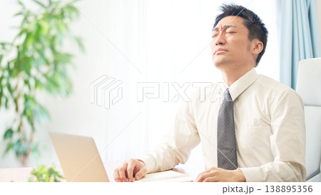 デスクワークの行き詰まりに目を閉じ苦悶の表情を浮かべる男性会社員 デスクワークの行き詰まりに目を閉じ苦悶の表情を浮かべる男性会社員 138895356