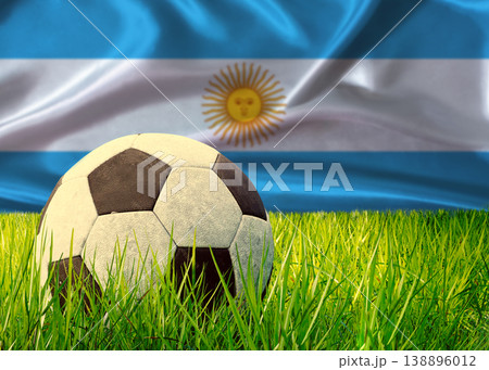 Soccer ball on the grass with Argentina flag in the background. Soccer ball on pitch against Argentine flag in the background Soccer ball on the grass with Argentina flag in the background. Soccer ball on pitch against Argentine flag in the background 138896012