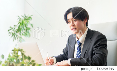 オンライン会議でメモを取りながら対応する会社員 138896145