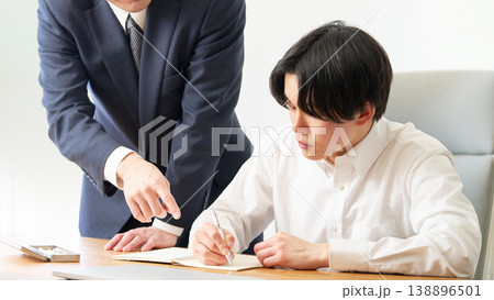 先生からマンツーマンで教わる若い男性 先生からマンツーマンで教わる若い男性 138896501