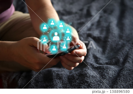 Close-up of male hands holding a smartphone with a glowing digital social network icon overlay. Concept of global communication, networking, human resources, and digital connectivity 138896580