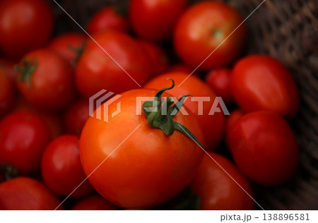 Close-up of fresh ripe red tomatoes in a rustic wicker basket. High angle view of organic harvest. Healthy eating and local farming concept with soft natural lighting 138896581