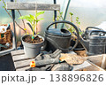 Garden tools and a seedling in a pot standing on a wooden chair.  138896826