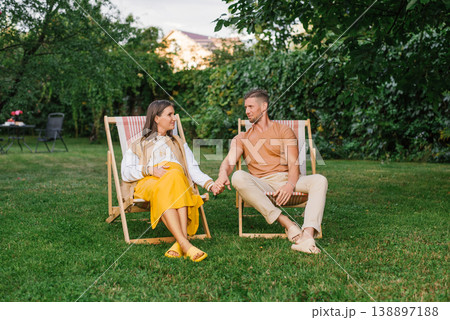 Pregnant Couple Relaxing Together In Summer Garden Pregnant Couple Relaxing Together In Summer Garden 138897188