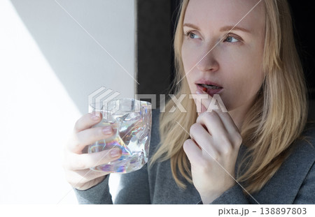 Woman taking iron supplement capsule with glass of water. Female health care, iron deficiency anemia treatment, vitamins and minerals intake for wellness. 138897803
