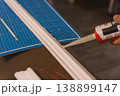 Hand applying construction adhesive to white molding on cutting mat, DIY renovation workspace 138899147