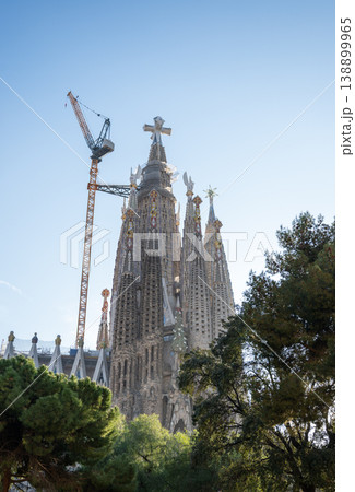 Sagrada Familia towers with construction crane and trees under blue sky in Barcelona Spain 138899965