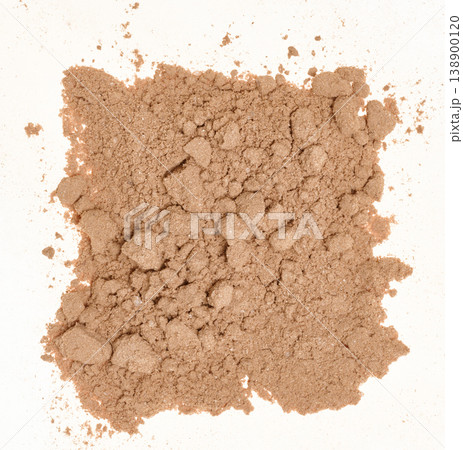 Spilled cocoa powder with small lumps, forming an uneven textured spot on a white background. Spilled cocoa powder with small lumps, forming an uneven textured spot on a white background. 138900120